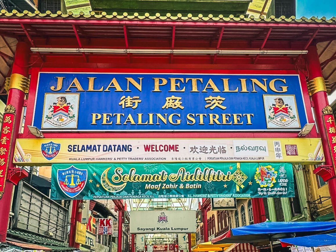 Affollato distretto commerciale con venditori di vari prodotti, dai vestiti al cibo.